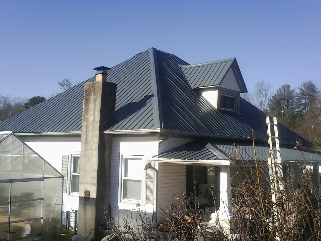Dark blue standing seam metal roof on a white farmhouse with dormer — Slate & Tile Roof Repair by Roofing Brothers in Nanty Glo
