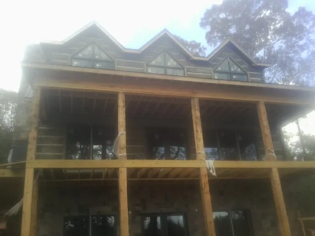 Dormers and porch framing on a large log home under construction — Roof Coating work by our crew in Nanty Glo