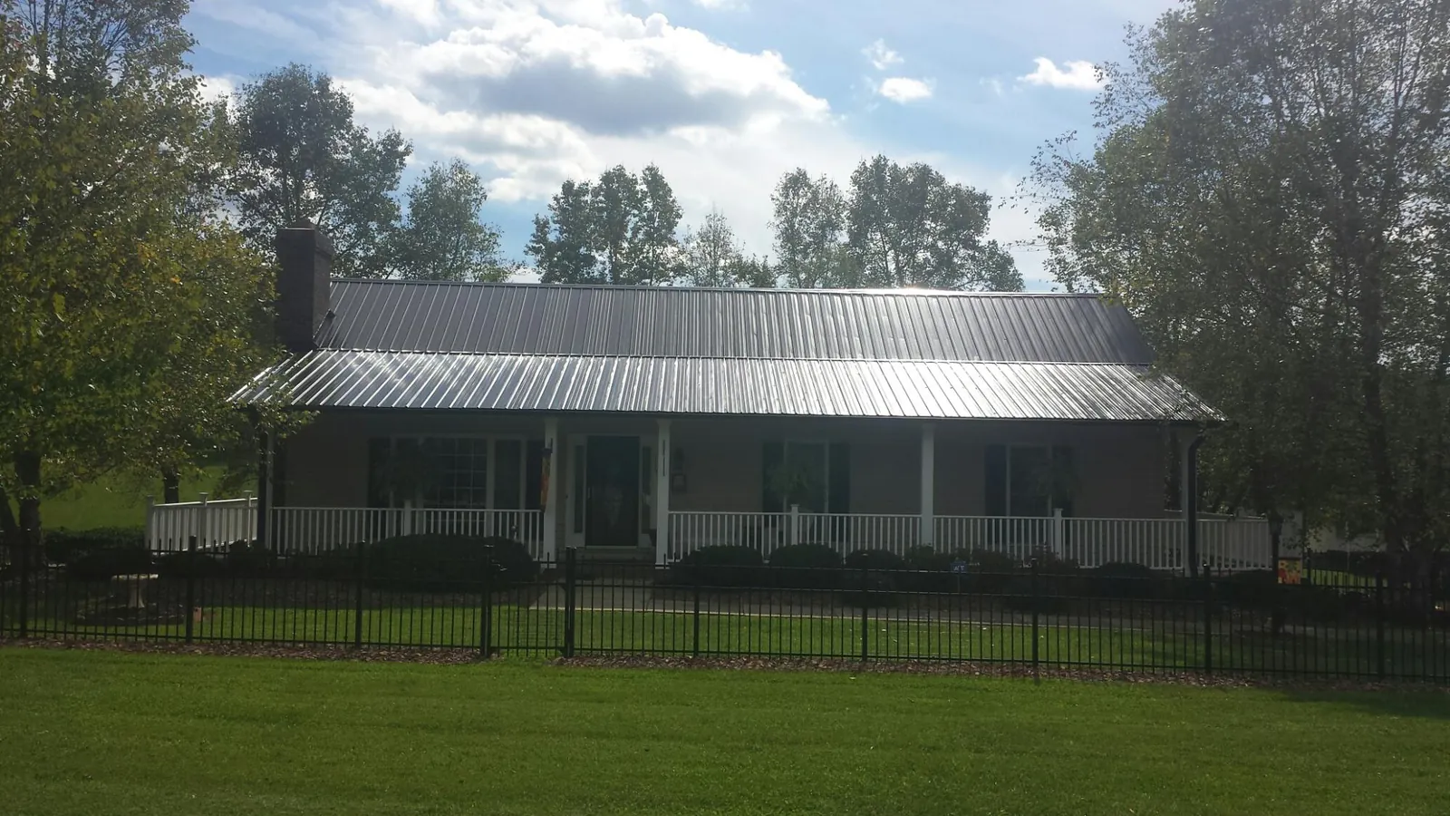 Gray metal roof on a brick ranch with a full width front porch — Gutter Guard Installation work by our crew in Nanty Glo