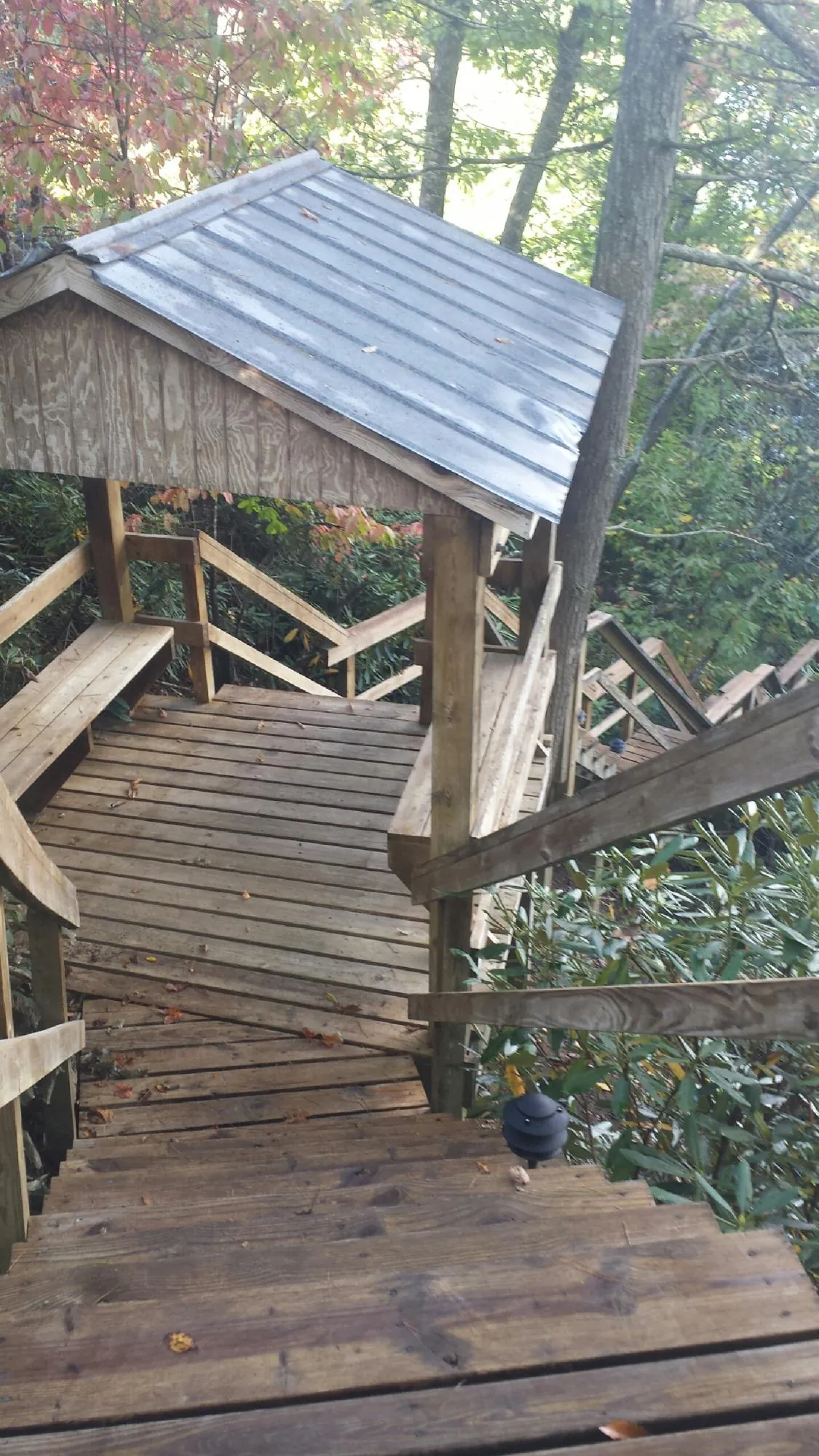 Metal roofed shelter over wooden steps on a wooded walkway — Skylight Repair & Installation work by our crew in Nanty Glo
