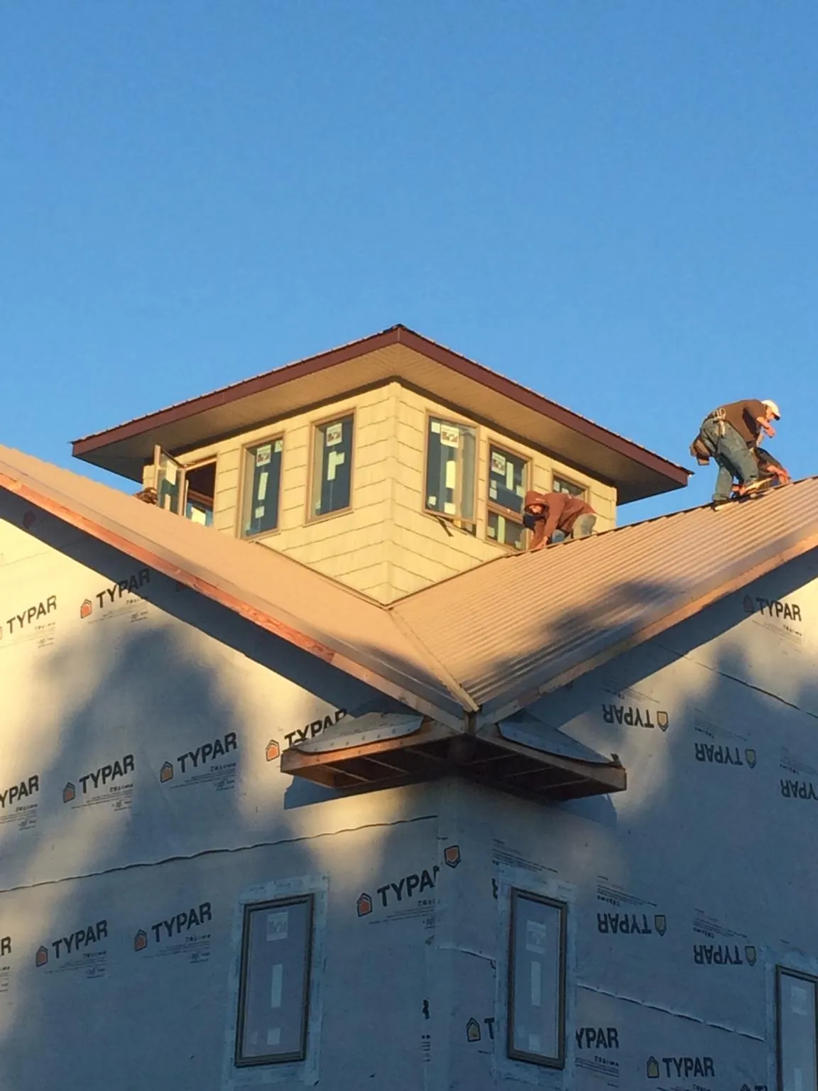 Roofers working around a rooftop cupola on a new metal roof at sunset — Roof Waterproofing in Nanty Glo by Roofing Brothers